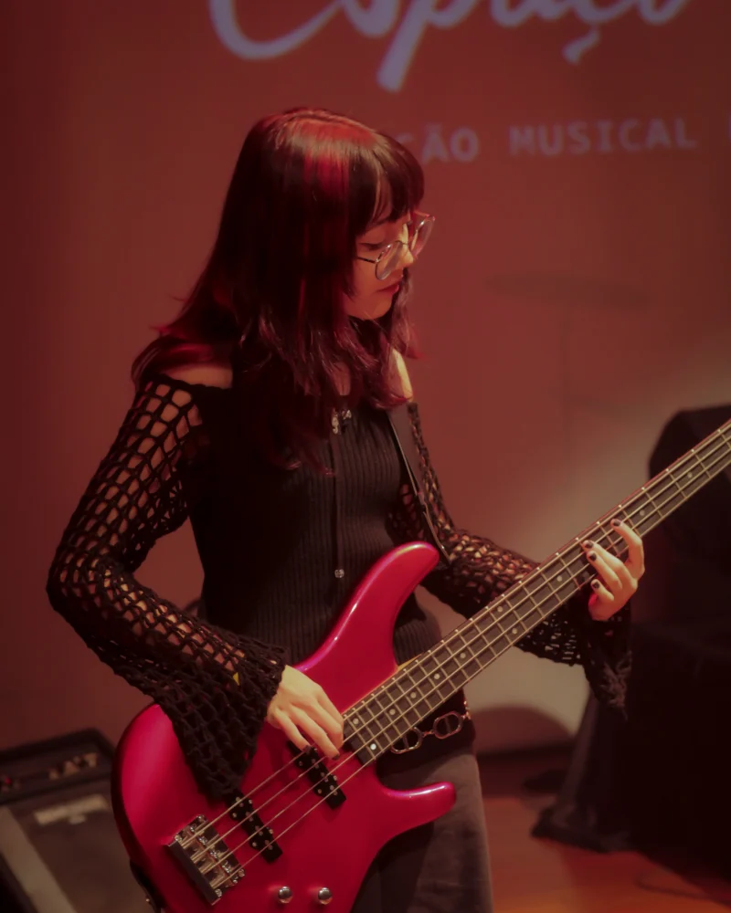 Aluna do Espaço Fermata tocando baixo no palco